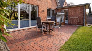 Een bakstenen huis met een patio, compleet met een tafel en stoelen, een schuifpui en een kleine tuin.