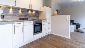 Een moderne keuken met witte kasten, een inbouwoven en een koffieapparaat.