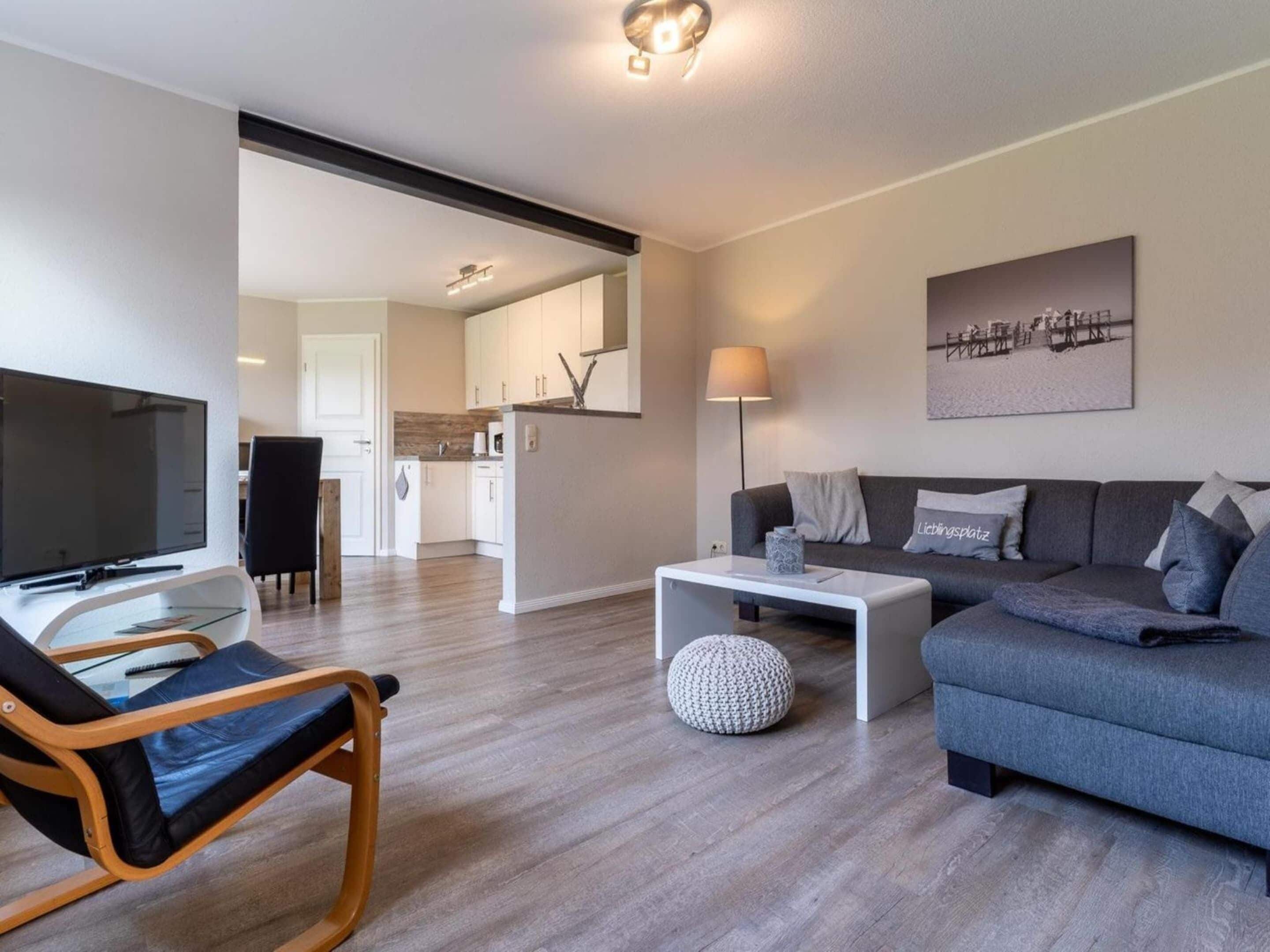 Ein modernes Wohnzimmer mit Sofa, Couchtisch, Fernseher und einem Essbereich mit Stuhl und Tisch.