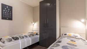 A bedroom with a bed, a wardrobe, and a wall-mounted light fixture. - Ferienwohnung Deichblume (St. Peter-Ording)