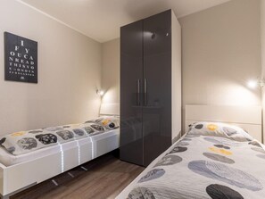 A bedroom with a bed, a wardrobe, and a wall-mounted light fixture. - Ferienwohnung Deichblume (St. Peter-Ording)