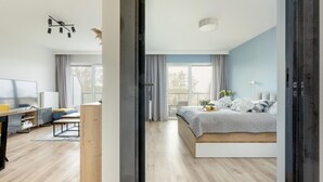 A modern bedroom with a bed, a desk, and a TV. - Apartment With a View of the River, Pool and Sauna (Dziwnów)