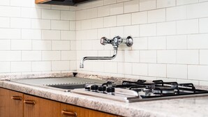Een keuken met witte metrotegels, houten kastjes, een roestvrijstalen spoelbak en een gasfornuis.