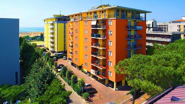 Een hotel met meerdere verdiepingen, balkons, een parkeerplaats en uitzicht op het strand.