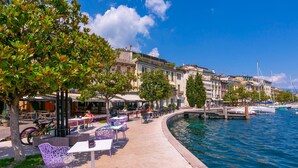 A waterfront café with outdoor seating, a dock, and boats in the background. - Laetitia Historic Center Fantastic View L (Salò)