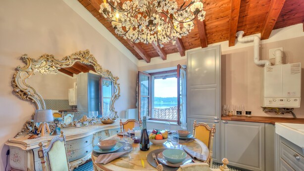 A dining area with ornate furniture, a chandelier, and a view of the outdoors. - Laetitia Historic Center Fantastic View L (Salò)