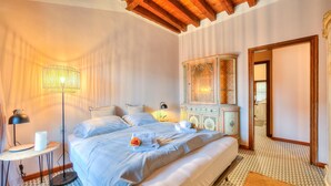 A bedroom with a large bed, bedside lamps, a round table with a lamp, and a cabinet with a mirror. - Laetitia Historic Center Fantastic View L (Salò)