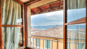 A window with a view of terracotta-roofed buildings and a wooden ceiling. - Laetitia Historic Center Fantastic View L (Salò)