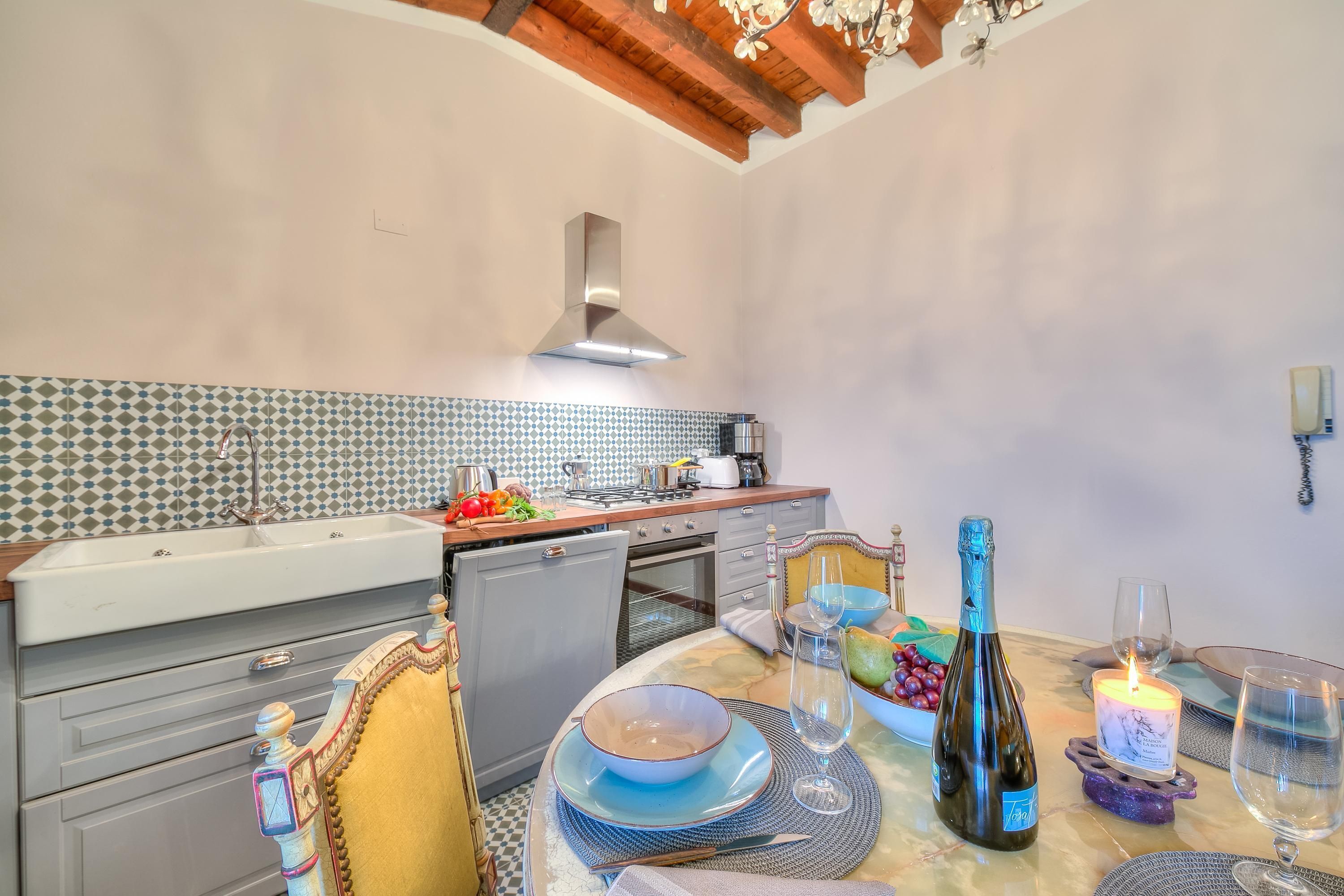A kitchen with a tiled backsplash, a built-in oven, and a dining area with a table set for two.
