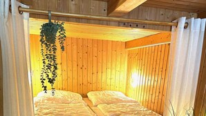 A loft-style bedroom with a wooden ceiling, a brick wall, and a ladder leading to a loft bed. - Bootshaus, Mirow (Mirow)