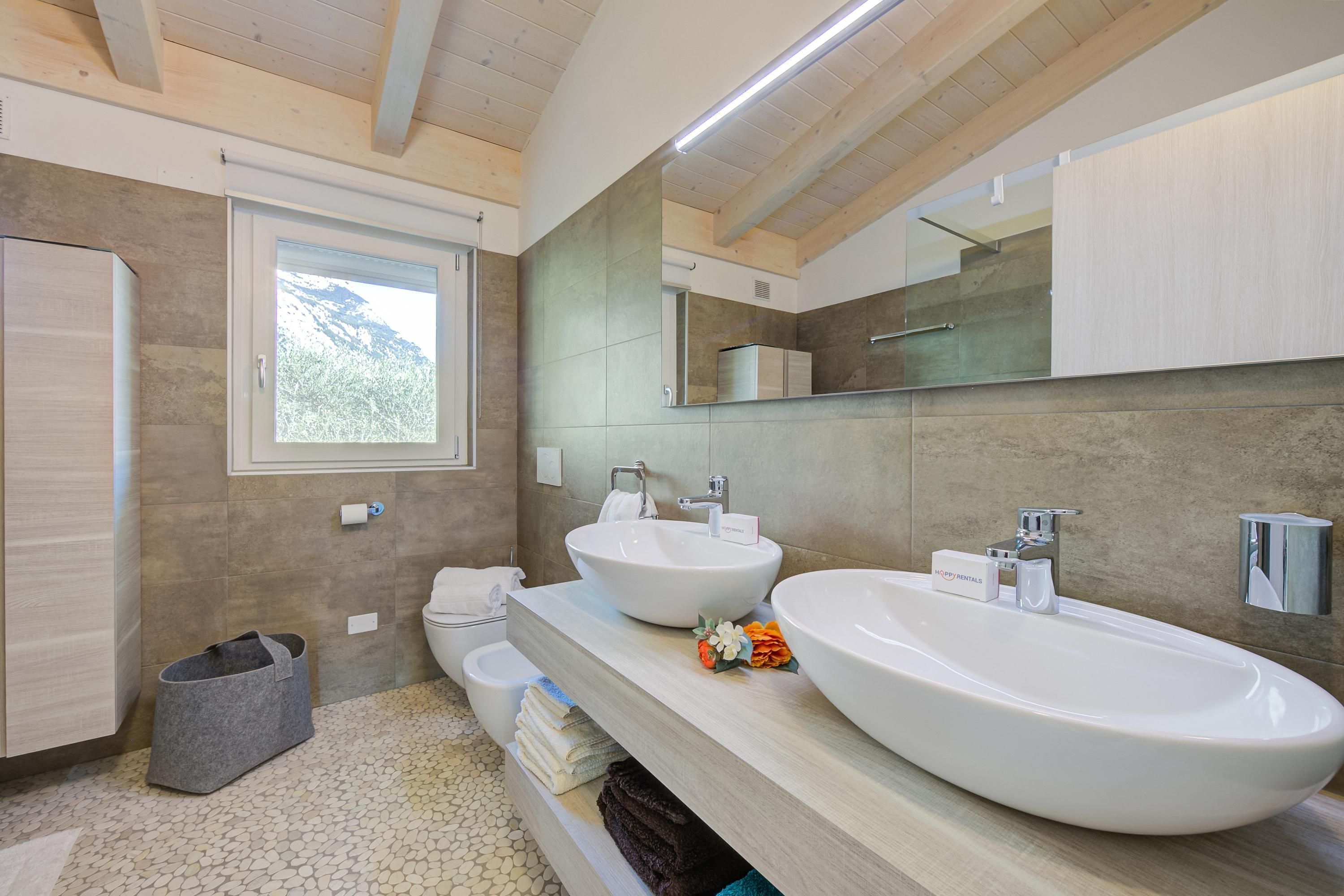 A modern bathroom with two large sinks, a mirror, and a window.