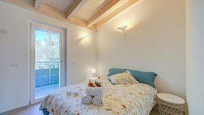 A bedroom with a bed, a bedside table, a lamp, and a window. - Mirabelle in Dro With 3 Bedrooms and 2 Bathrooms (Dro)