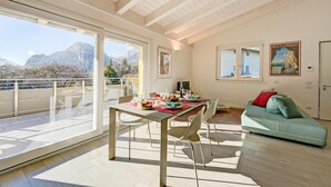 A spacious living area with a balcony, a dining table set with plates and glasses, and a green sofa. - Mirabelle in Dro With 3 Bedrooms and 2 Bathrooms (Dro)