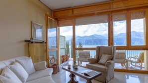 Amplia sala de estar con vistas a montañas a través de amplias ventanas, chimenea y un espacio de descanso acogedor.