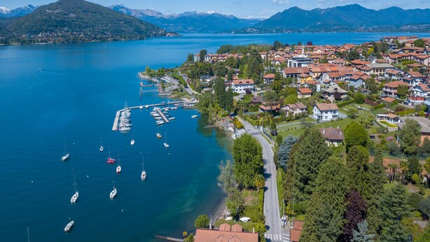 A coastal town with a marina, houses, and mountains in the background. - Cedar House Villa Few Minutes From Lake (Angera)