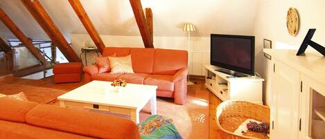 A cozy living room with a sofa, a coffee table, a television, and a wicker basket.