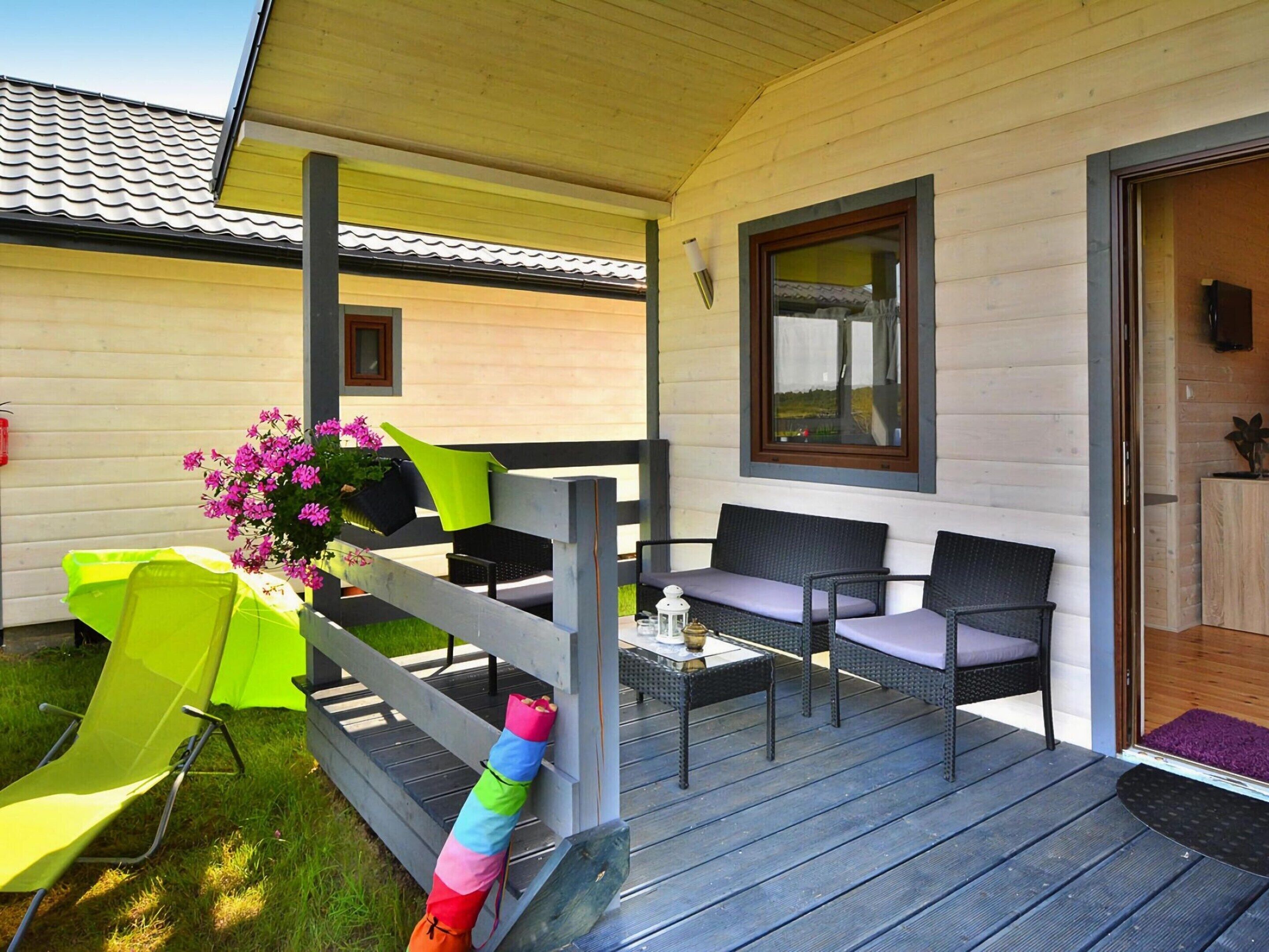 A covered outdoor seating area with a wooden deck, a table, and two chairs.
