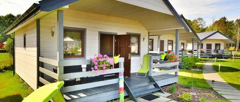 A single-story house with a porch, a small garden, and a blue inflatable pool.