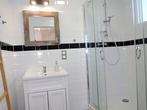 A bathroom with a glass shower enclosure, a white sink with a mirror above it, and a black and white tiled backsplash. - Cottage in Niechorze Near Baltic Sea Beach (Rewal)