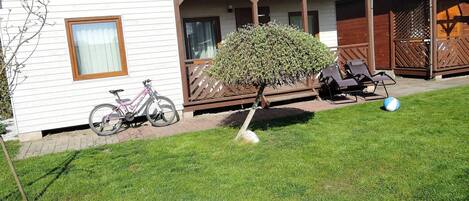 A single-story house with a porch, a small tree, and a bicycle parked outside.