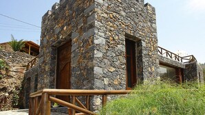 A stone building with wooden doors and windows, a wooden railing, and a stone wall. - Holiday Home in Vera de Erques (Guia de Isora)