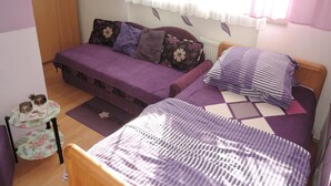 A bedroom with a bed, a sofa bed, a small table with bowls, and a radiator. - Holiday Home in Dziwnowek Near the Beach (Dziwnów)
