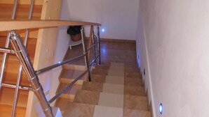 A staircase with a wooden handrail and metal balusters, leading to a landing with a potted plant. - Holiday Home in Dziwnowek Near the Beach (Dziwnów)