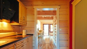 A wooden interior with a kitchen area, wooden cabinets, and a dining table. - Comfortable Holiday Home Close to the Beach (Ustronie Morskie)
