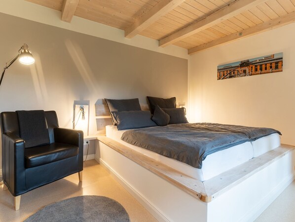 A bedroom with a loft bed, a black leather chair, a desk, and a painting on the wall. - Reetgedecktes Ferienhaus in Westerhever mit Sauna (Westerhever)