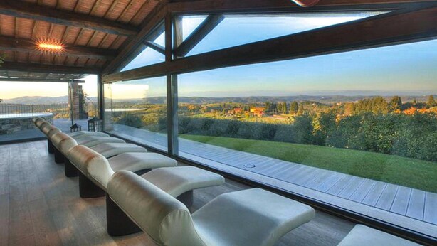 Ein moderner Sitzbereich im Freien mit Blick auf einen angelegten Garten und sanfte Hügel in der Ferne.
