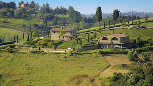 Ländliche Landschaft mit Steinhäusern, umgeben von üppigem Grün und sanften Hügeln.