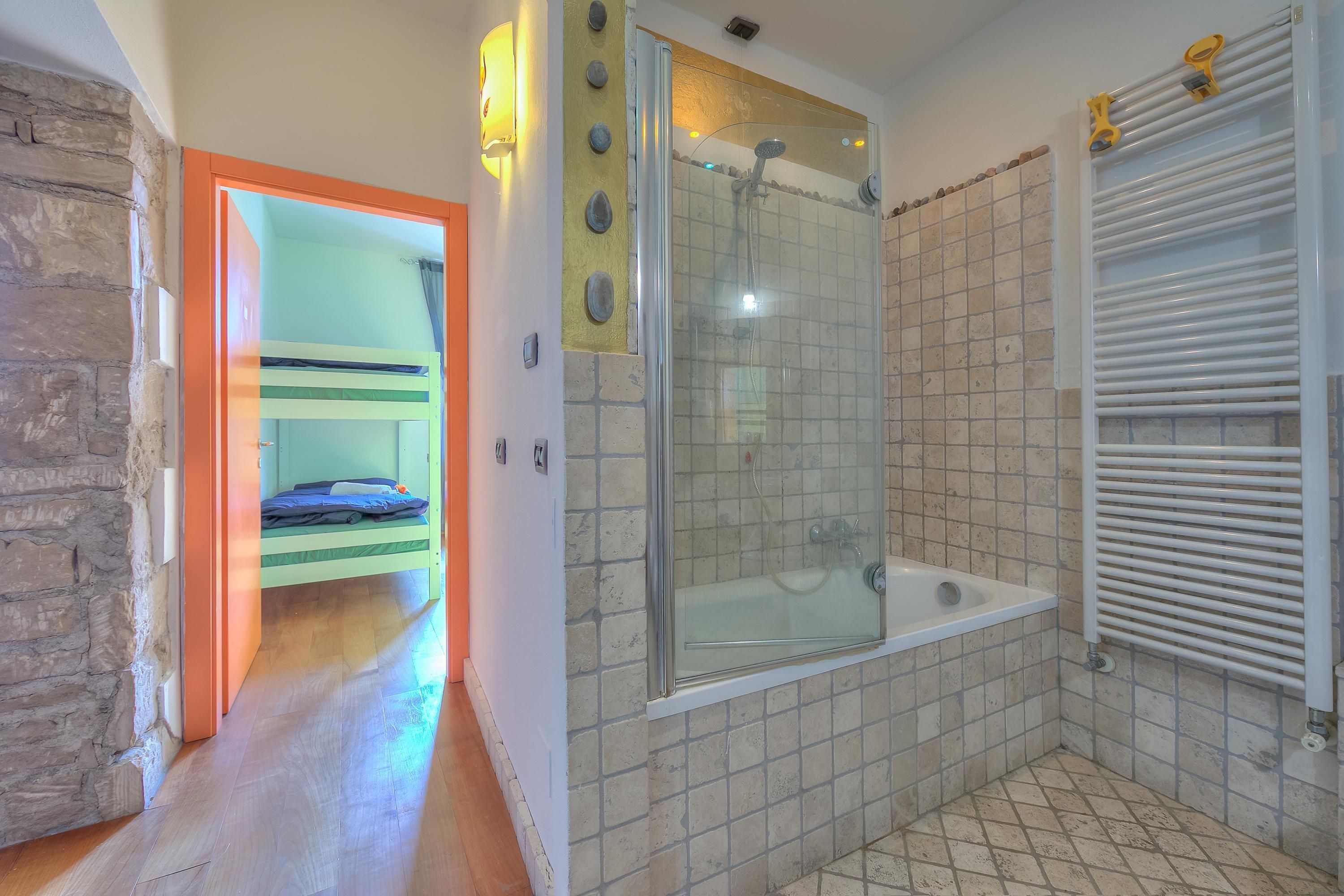 Une salle de bain avec une douche à parois de verre, une baignoire et un sol carrelé.