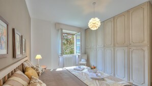 A bedroom with a bed, bedside table, lamp, window, and wardrobe. - Elena Apartment - Family Friendly (Salò)