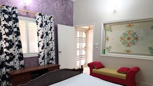 A bedroom with a bed, a bedside table, a wardrobe, and a window with curtains.