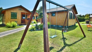 Een houten chalet met een schommel voor de deur.
