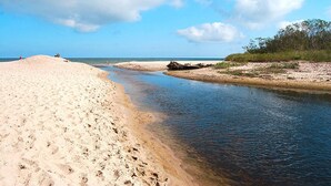 Een zandstrand met een rustig wateroppervlak en een heldere lucht.