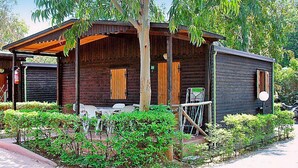 Un rustico chalet in legno con un portico coperto, un tavolino e delle sedie.