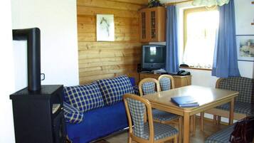 A cozy room with a blue sofa, wooden dining table, chairs, a television, and a fireplace.