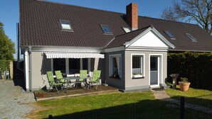 Ein zweistöckiges Haus mit überdachter Terrasse, umzäunter Hinterhof und kleinem Garten.