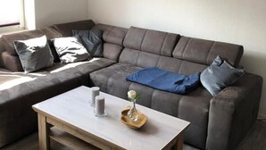 Ein modernes Wohnzimmer mit einem Ecksofa, einem Couchtisch und einem Gemälde an der Wand.