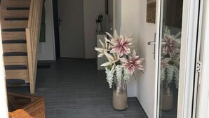 Ein Flur mit einer Holztreppe, einem Blumentopf und einer Tür zu einem anderen Raum.