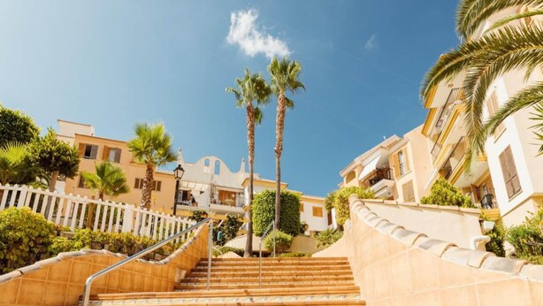 A set of outdoor stairs leading to a building with balconies, surrounded by palm trees and a clear sky. - Apartment in Pueblo Salado, Mazarron (Mazarrón)