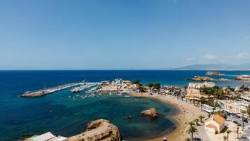 A coastal town with a marina, sandy beach, and buildings along the shore.