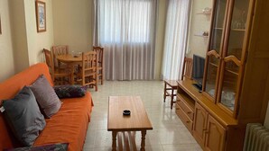 A living room with a sofa, a wooden table, a television, and a cabinet. - Apartment in Pueblo Salado, Mazarron (Mazarrón)