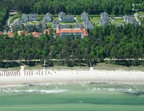 Vista aérea de una zona costera con varios edificios, una playa y una área boscosa.