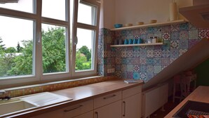 Una cocina con ventana, armarios blancos, una encimera y salpicadero de azulejos.