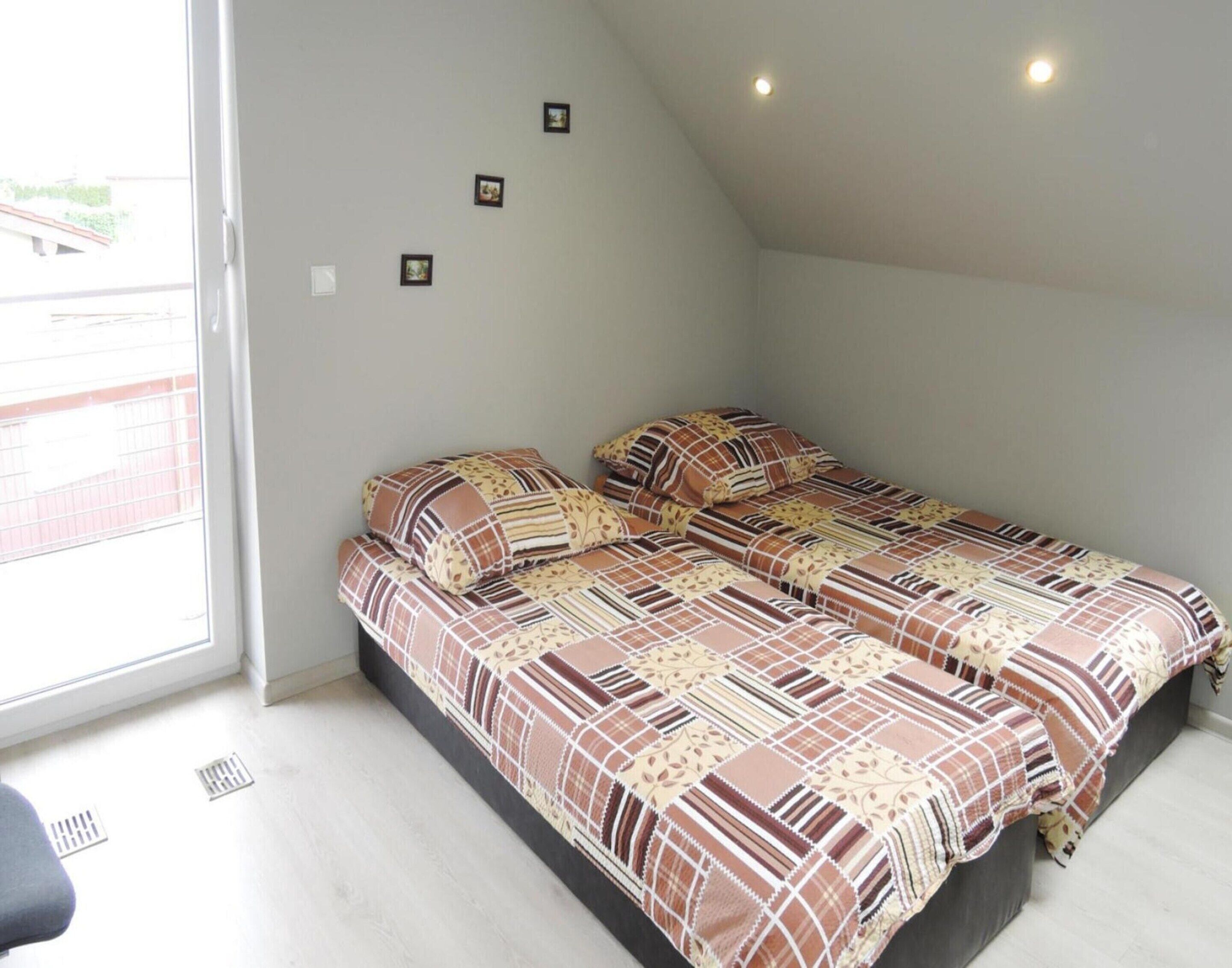 Una camera da letto con due letti, una finestra e un soffitto spiovente.