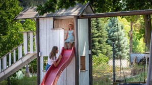 Une cabane en bois pour enfants, avec un toboggan rouge et un petit porche.