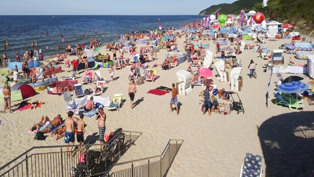 Une plage bondée, avec de nombreux parasols et des chaises de plage.
