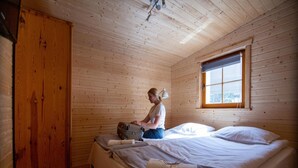 Une chambre dans un chalet en bois, avec un lit, une valise et une armoire.